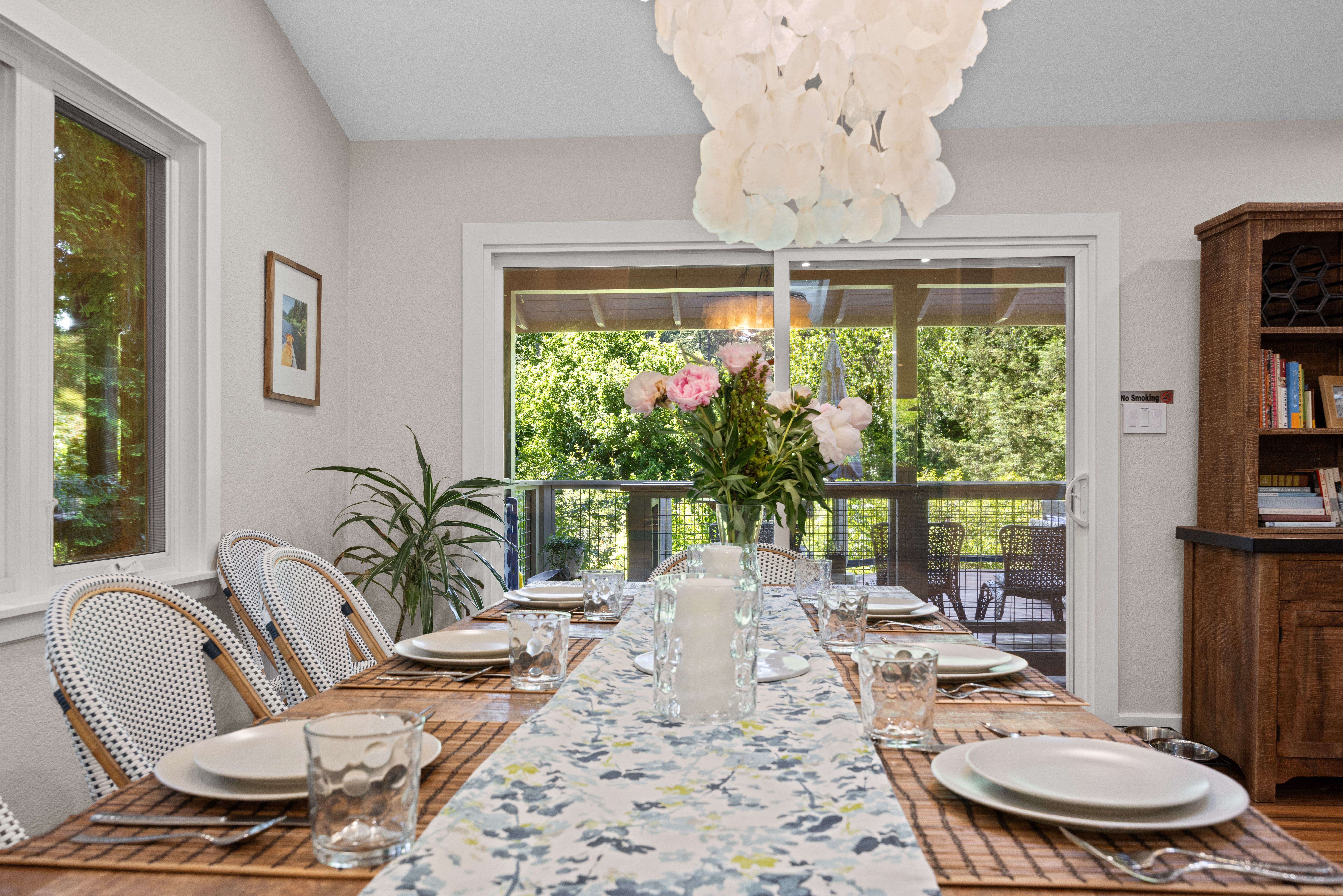 Bright dining room with deck access, lush views, and seating for a group