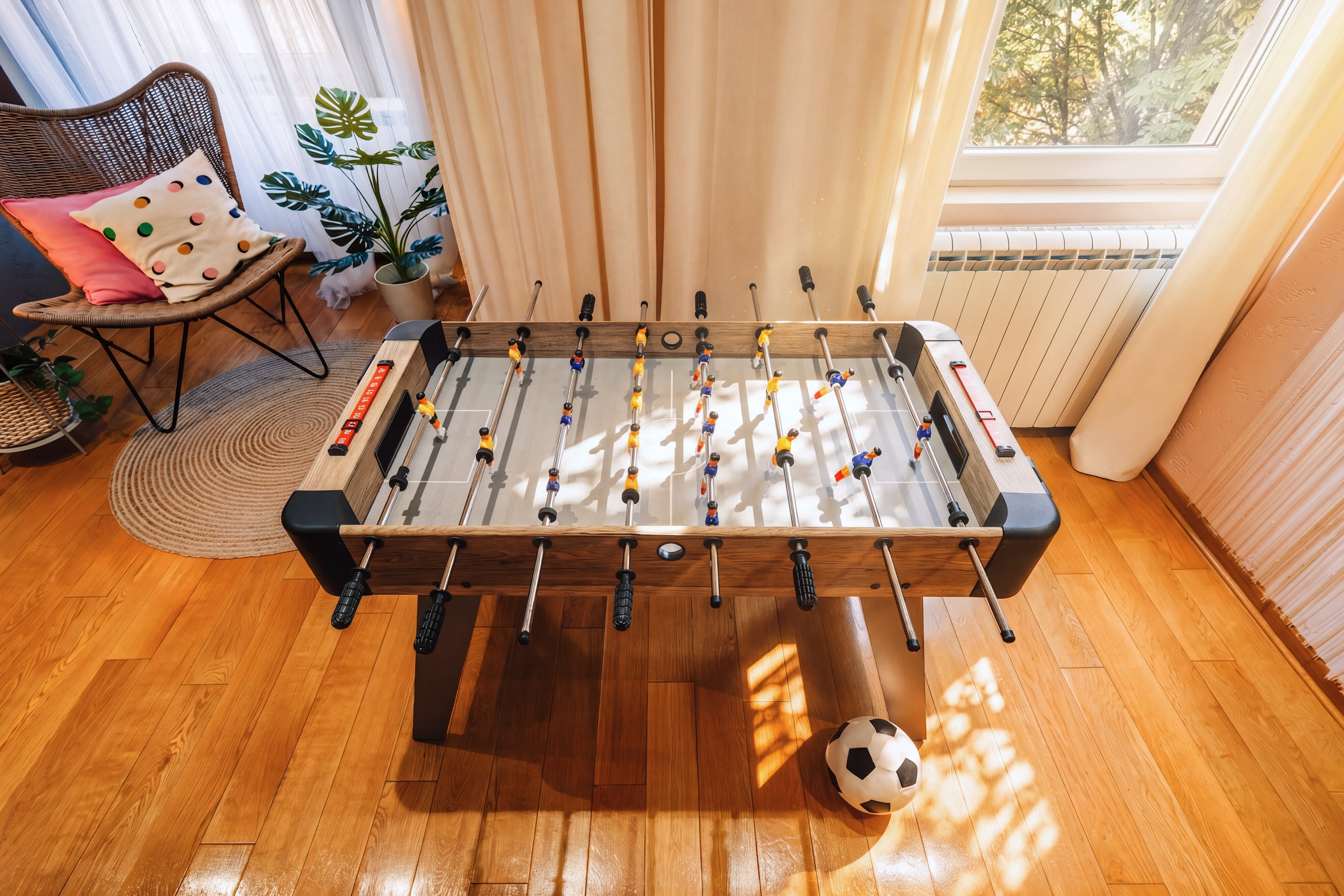 Sunny game nook with foosball table, hardwood floors, and cozy lounge accents
