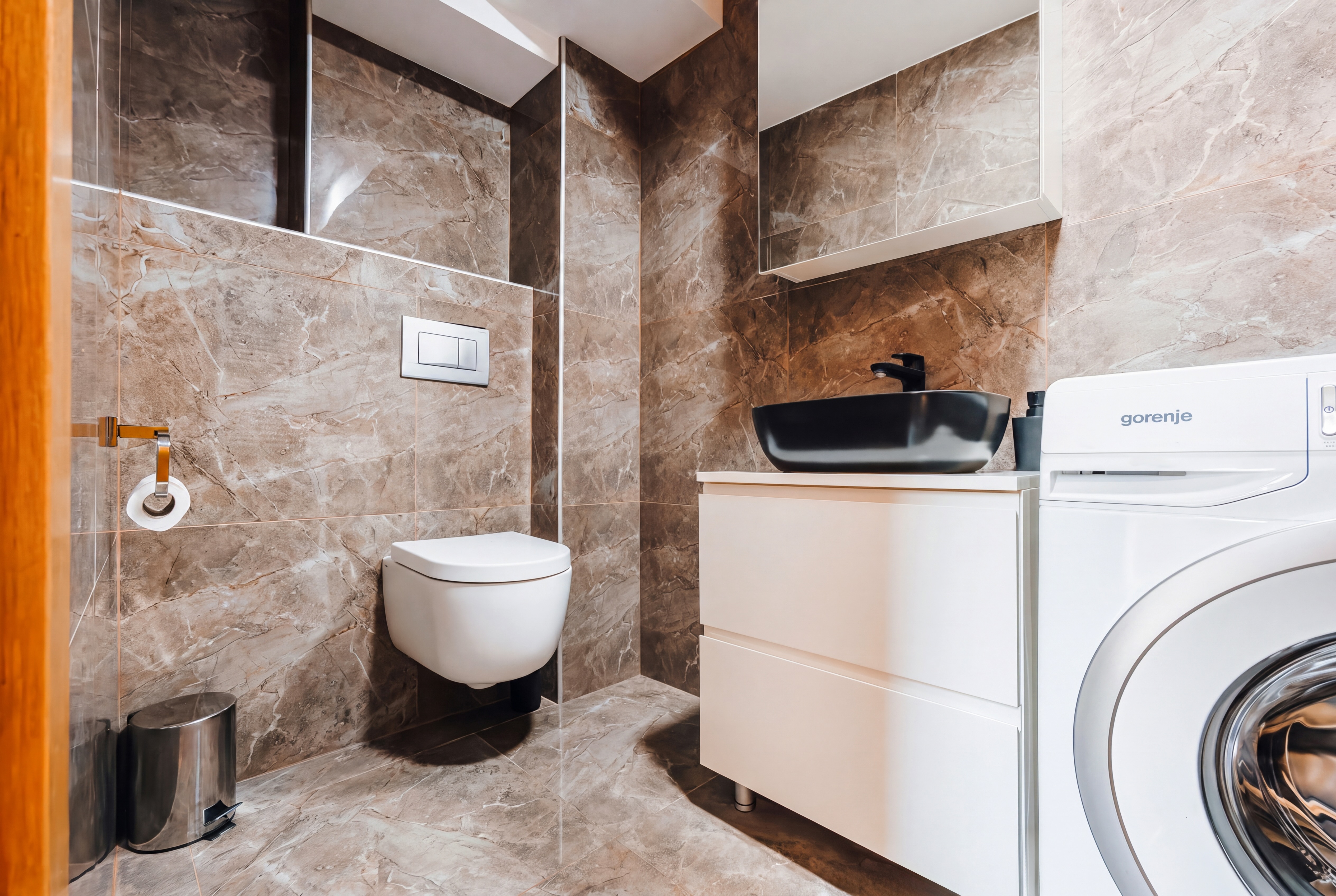 Modern marble bathroom with washer, sleek vanity, and designer finishes