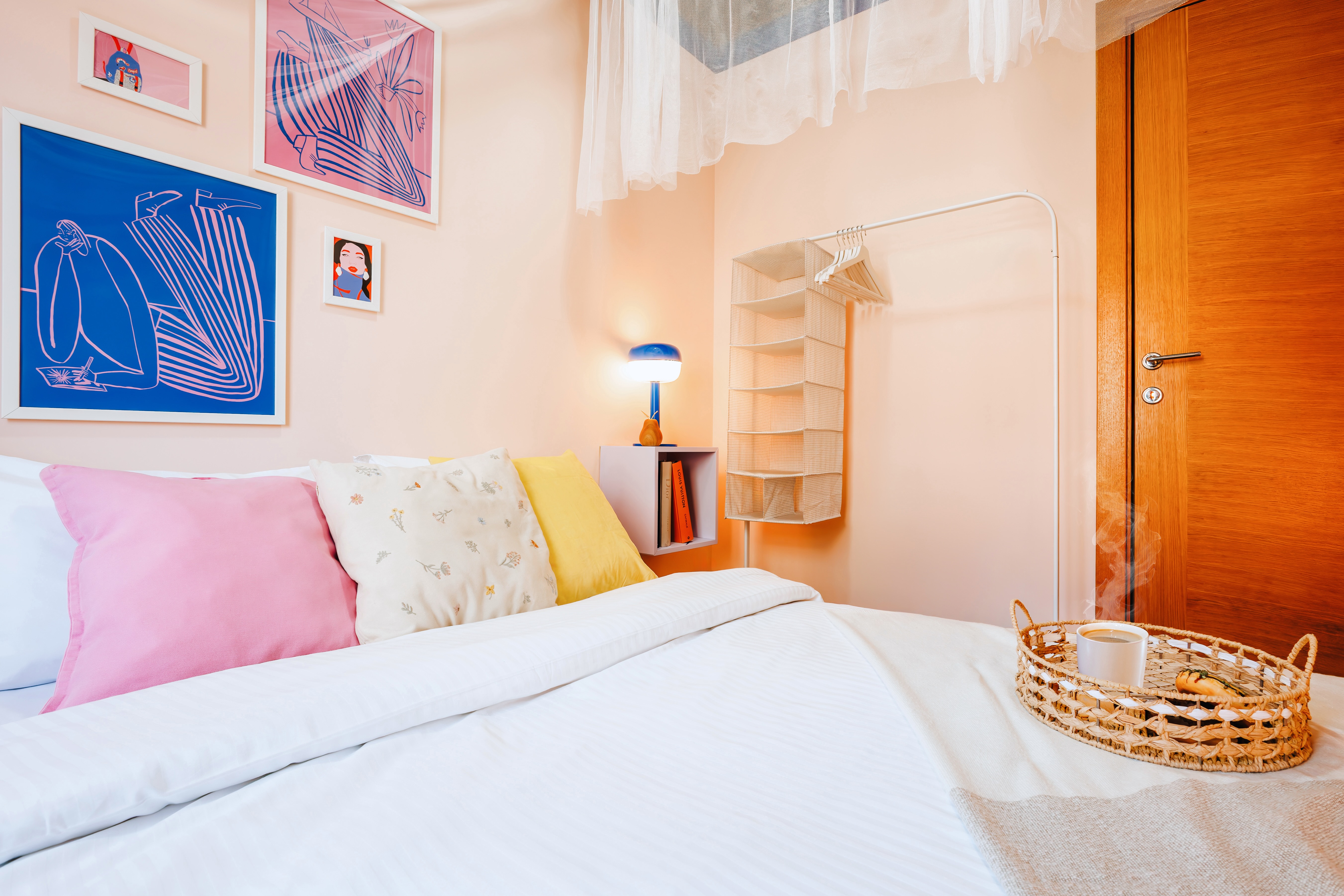 Cozy pastel bedroom with stylish art, warm lighting, and guest-friendly storage