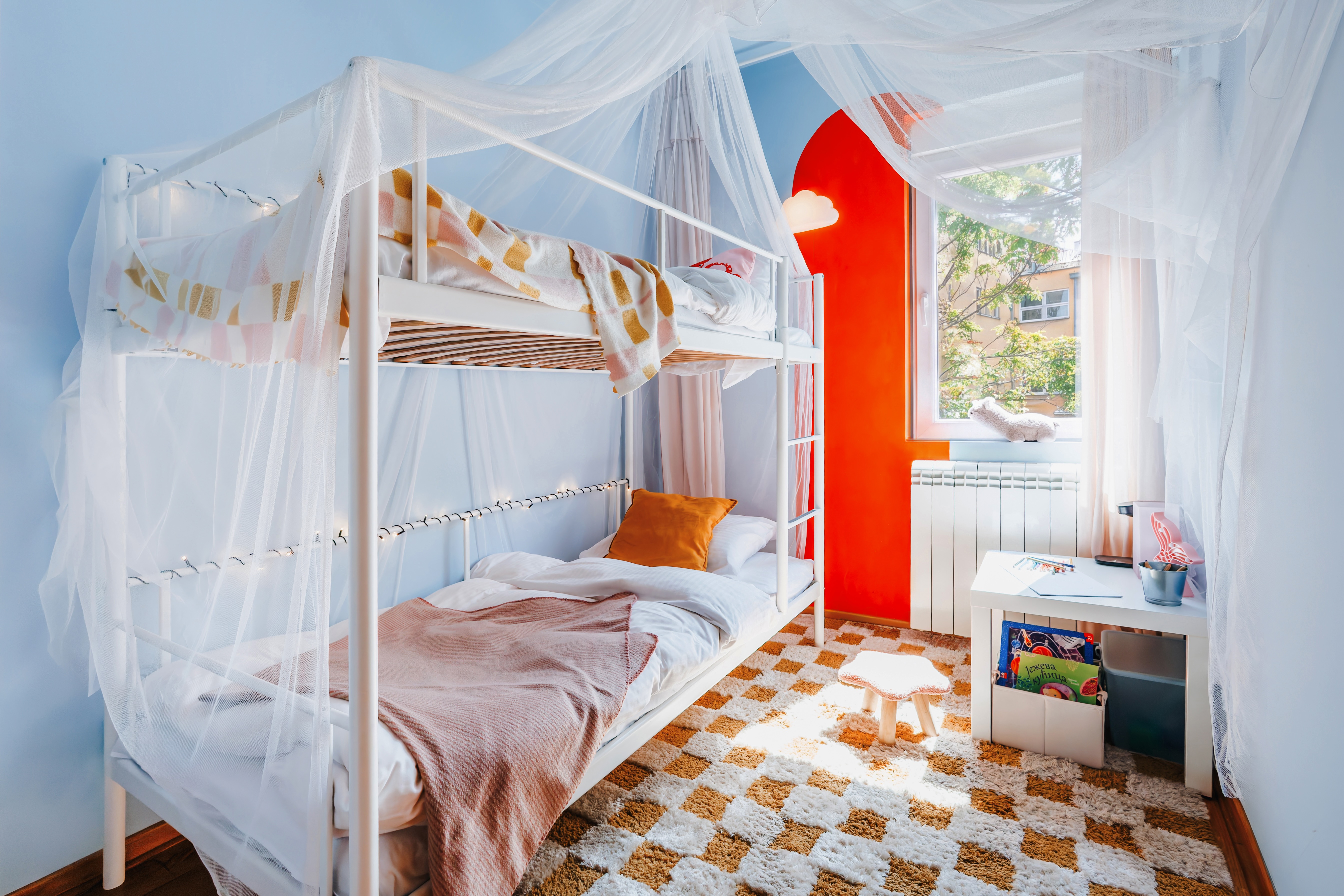 Bright kids’ room with whimsical bunk beds, canopy drapes, and play area