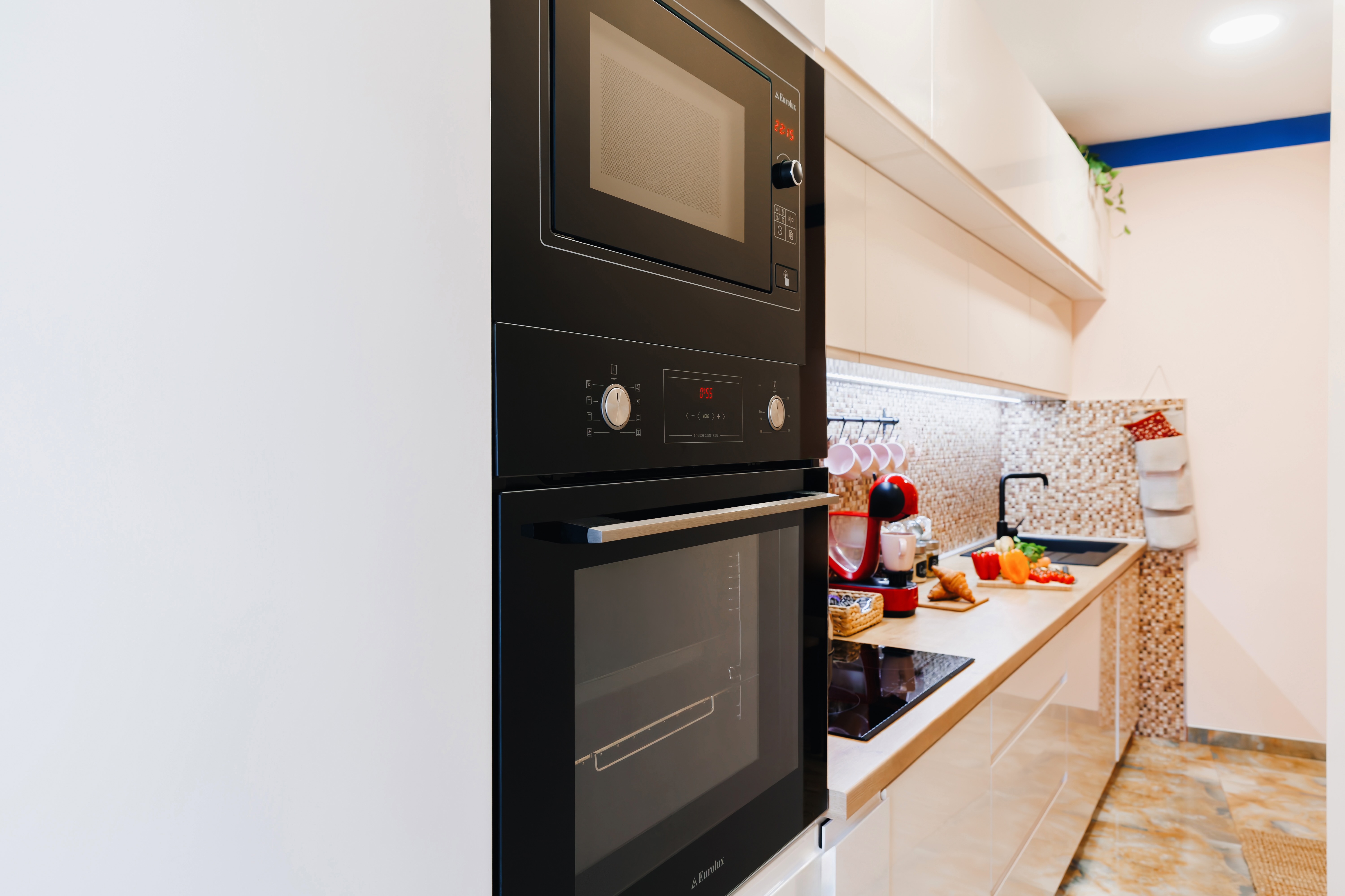 Modern galley kitchen with built-in oven, microwave, and bright finishes