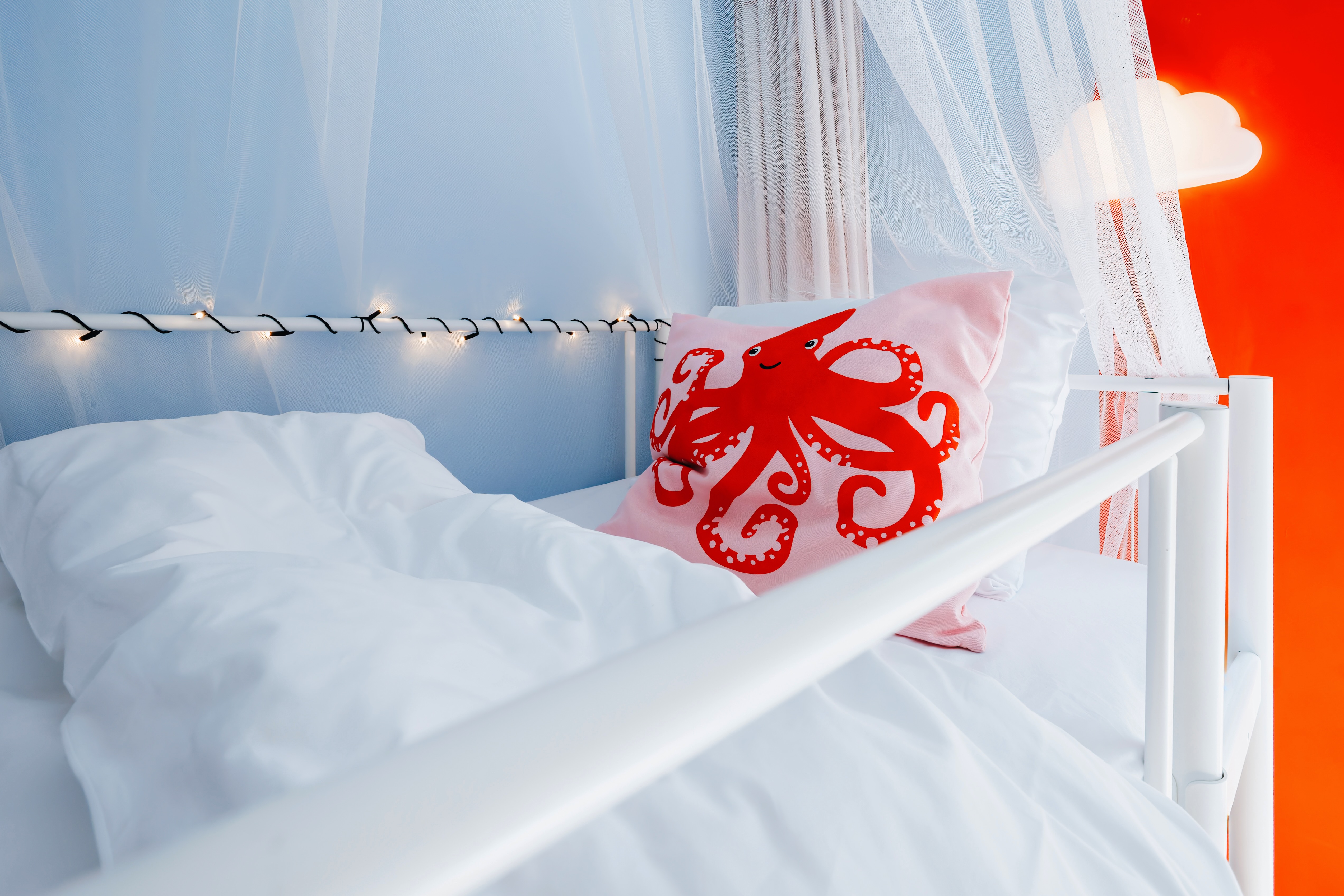 Whimsical canopy bed with soft lights and playful coastal charm