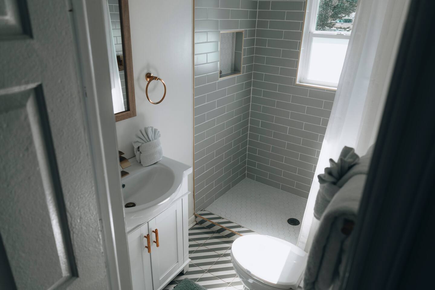 Curbless shower with built-in niche beside patterned tile flooring