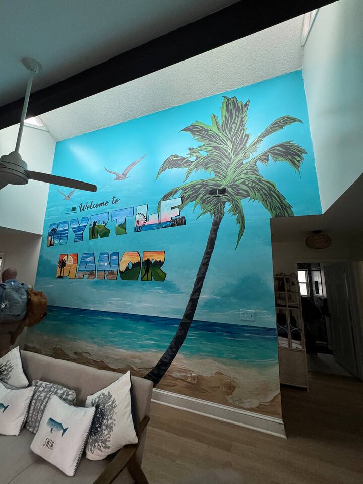 Painted palm mural rising to the vaulted living room ceiling