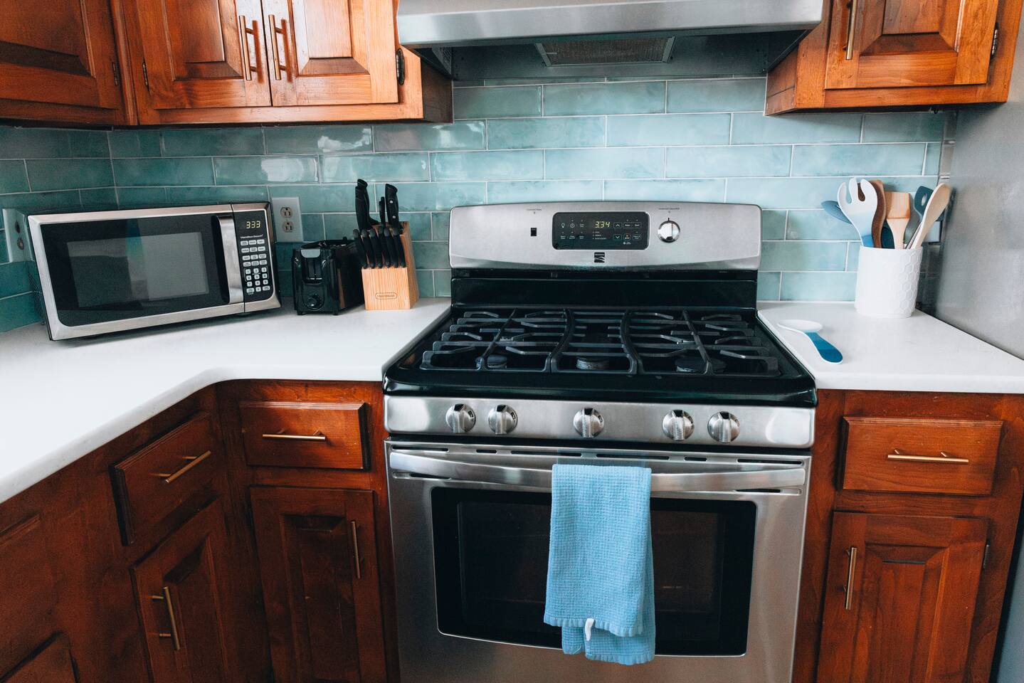 Five-burner gas range with utensils and range hood above