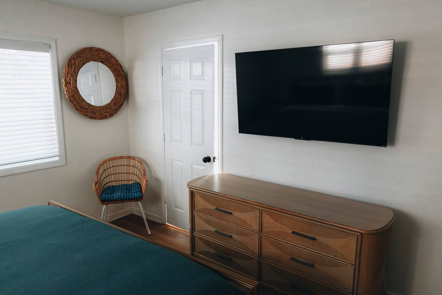 Bedroom with wall-mounted television, rattan dresser and woven mirror