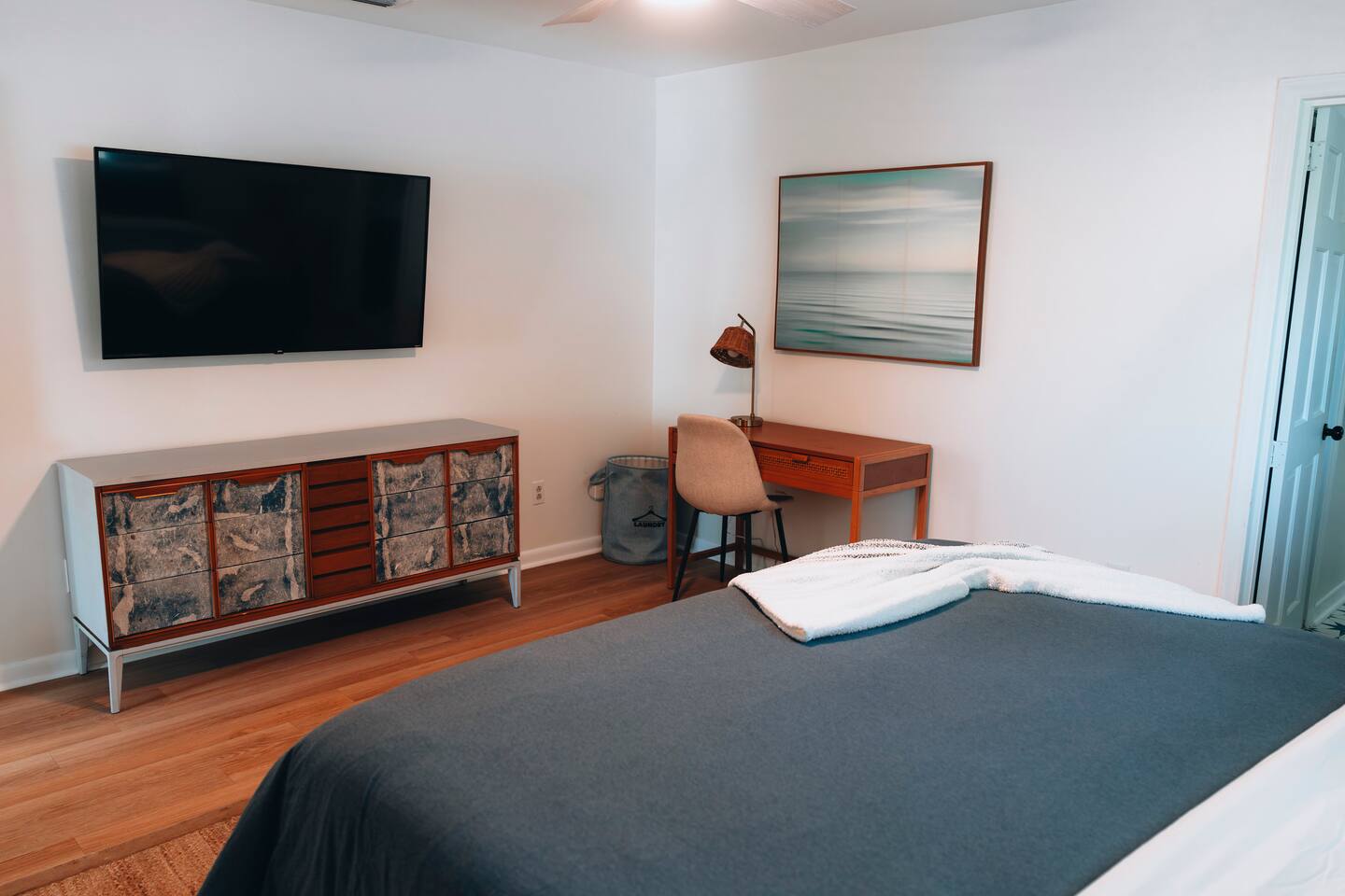 Bedroom with wall-mounted TV, wide dresser and a desk corner