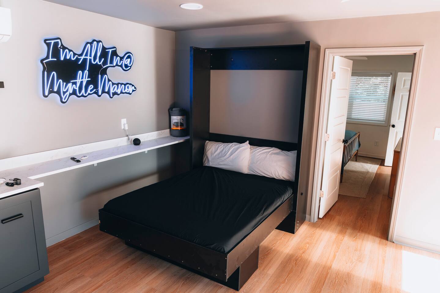 Murphy bed folded down beside the neon Myrtle Manor sign