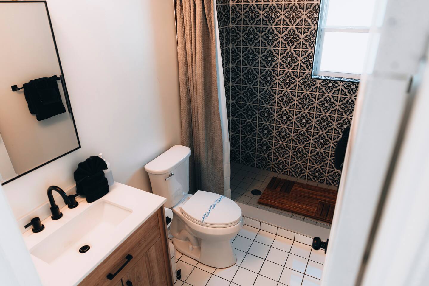Bathroom with white tile floor and a curtained walk-in shower