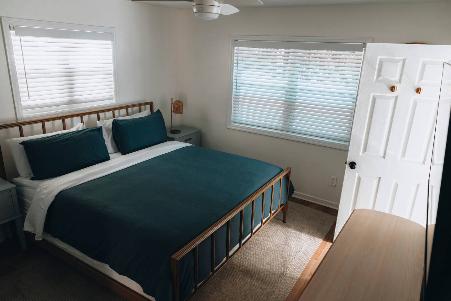 Bedroom with a queen bed, ceiling fan and two shuttered windows