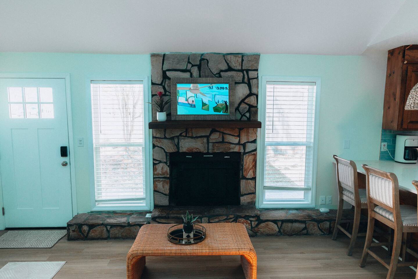 Living room with stone fireplace, mounted TV and wicker coffee table
