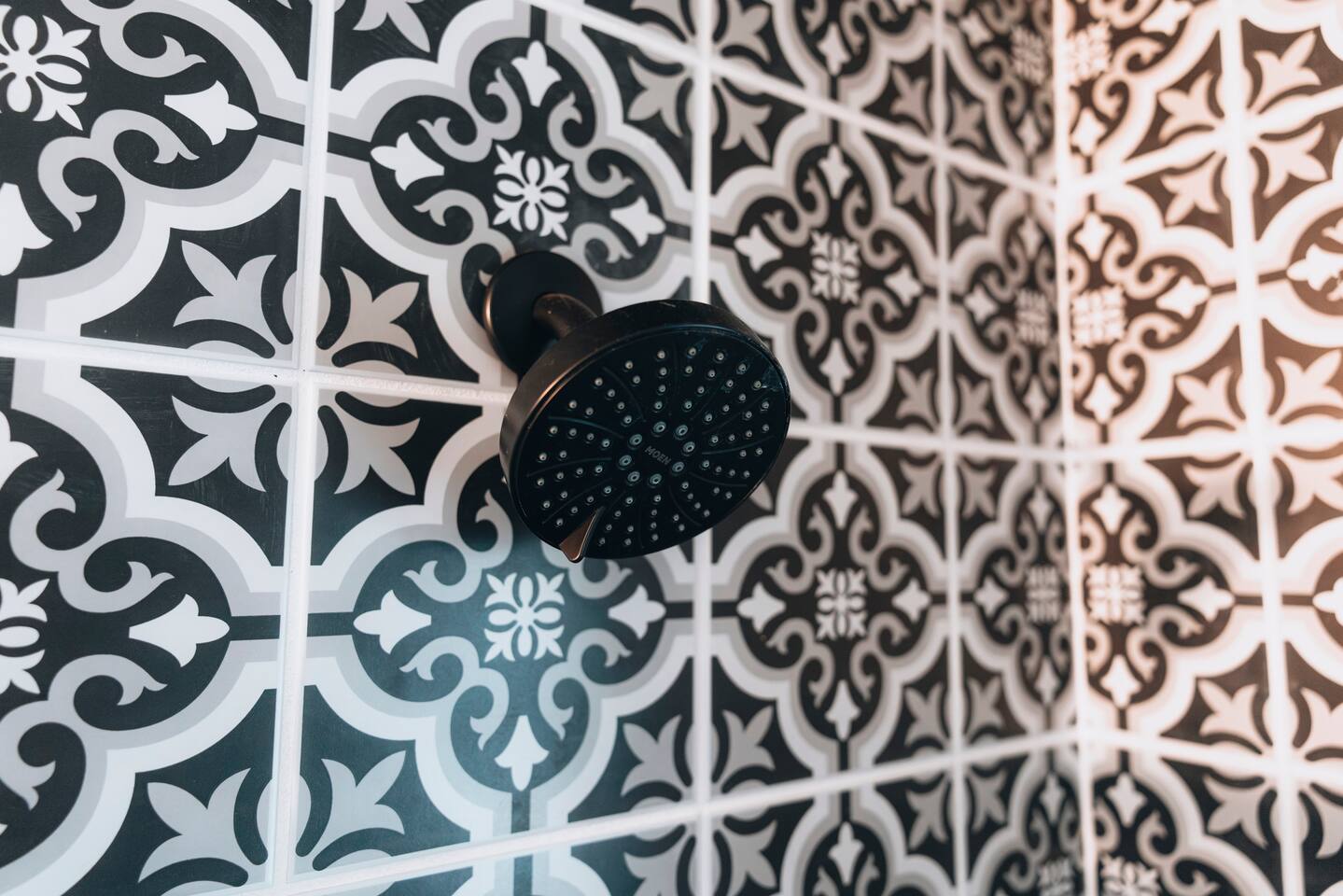 Black shower head against the shower's patterned black and white tile
