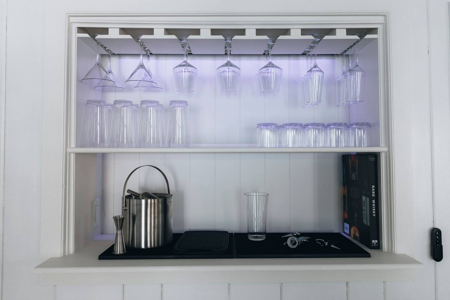 Lit bar niche with hanging stemware, ice bucket and bar tools
