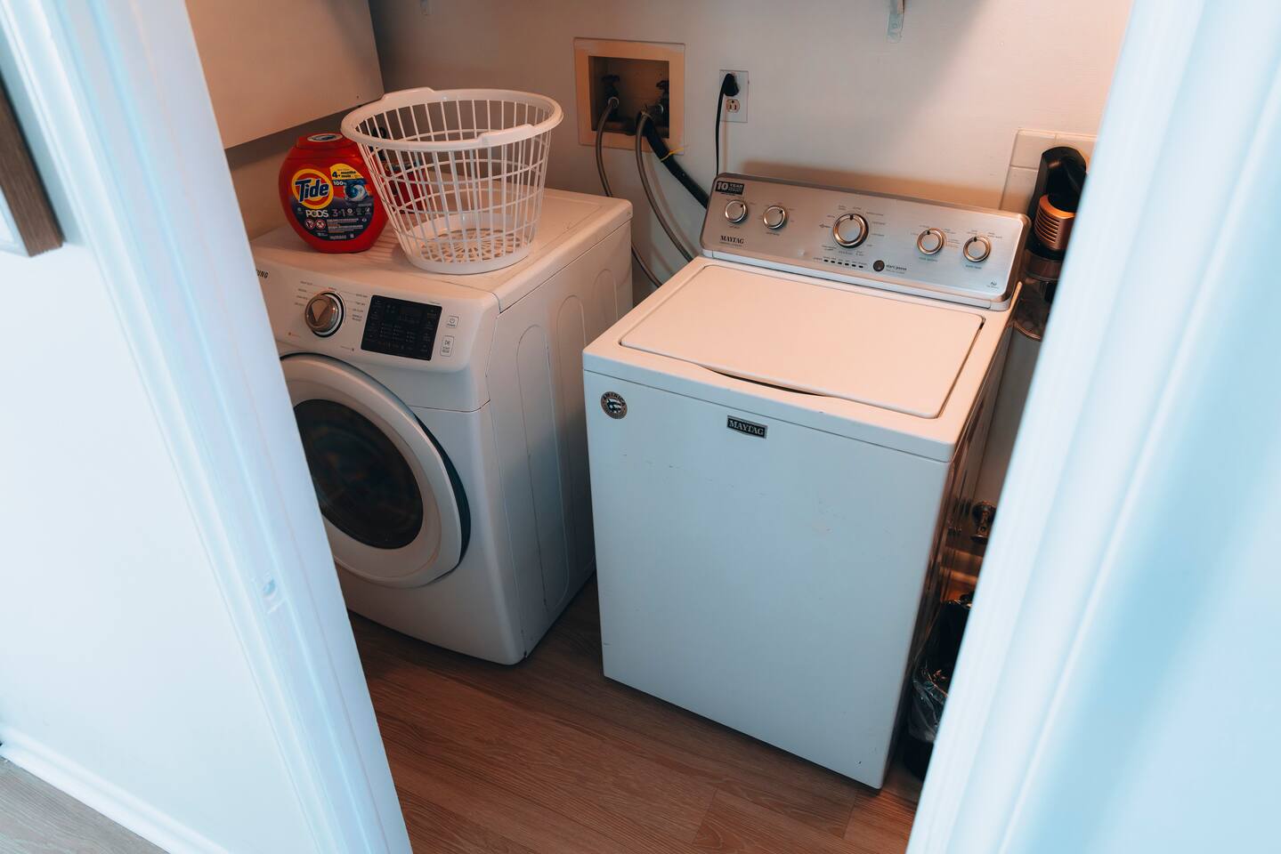 Laundry closet with a full-size washer, dryer, detergent and basket