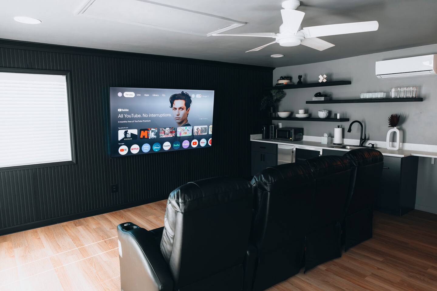 Media room with reclining leather seating facing a large smart TV