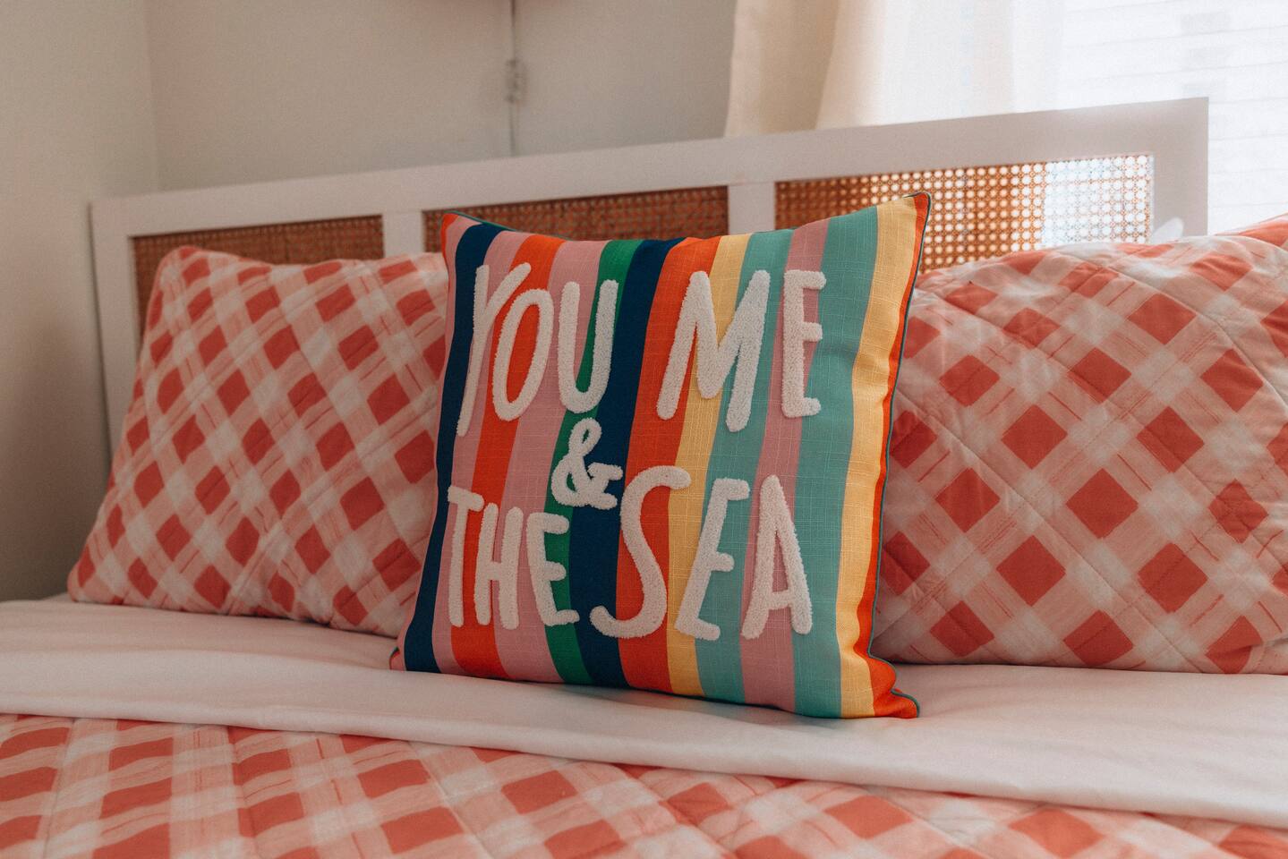 Caned headboard with checked pillows and a striped accent cushion