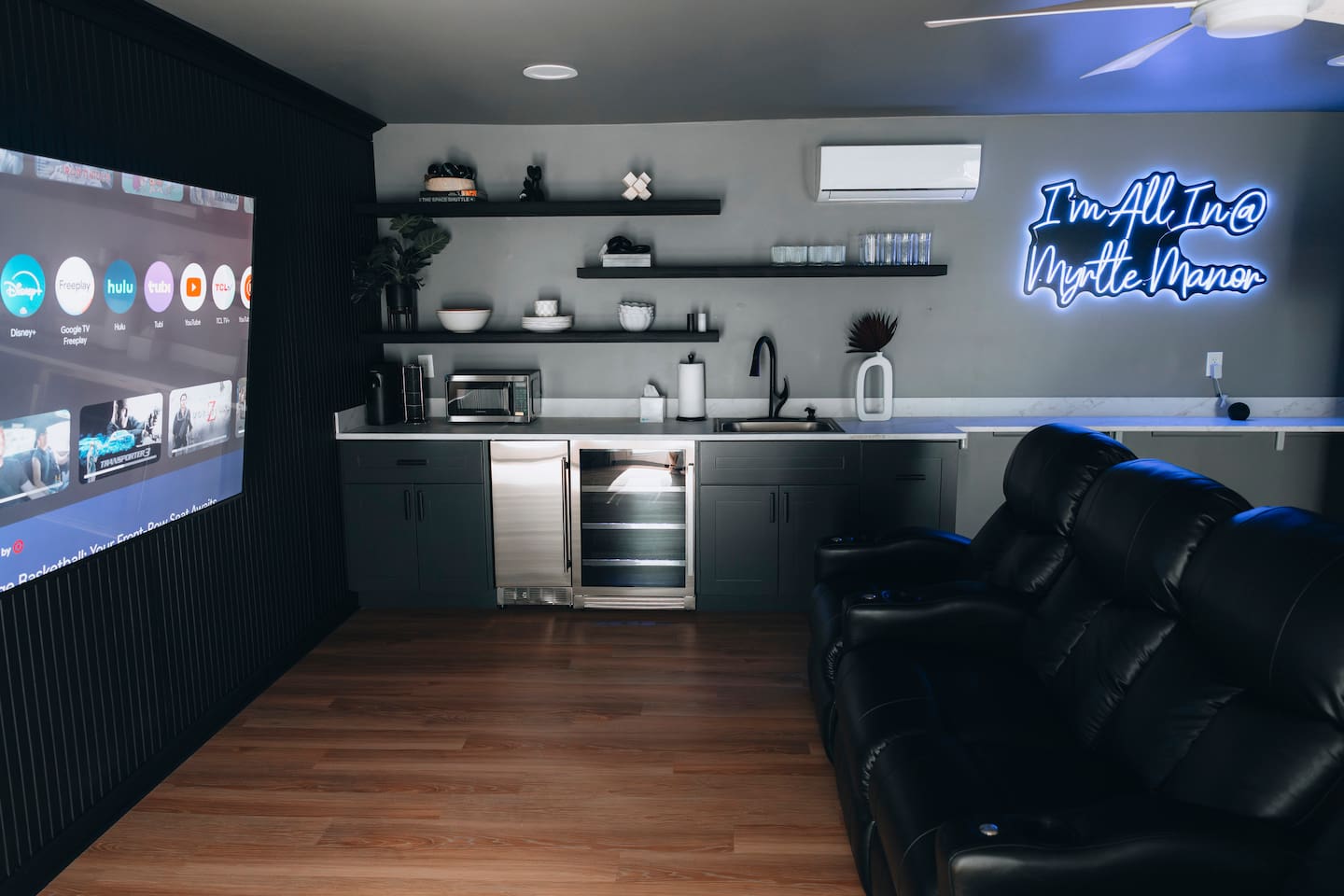 Media room with reclining leather seating, wall-mounted screen and wet bar