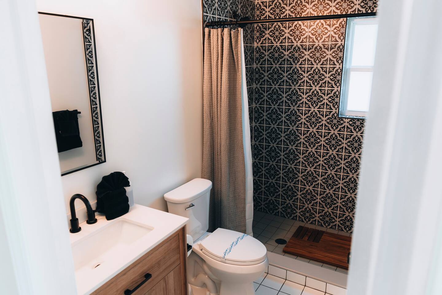 Shower with teak mat and tiled walls, seen from the doorway
