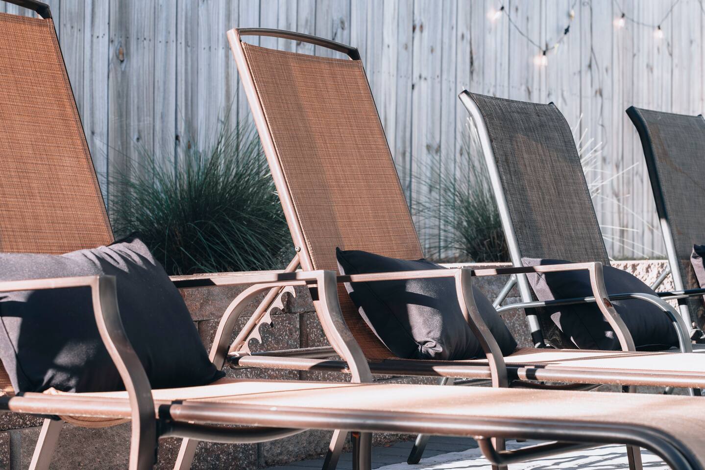 A row of sling loungers with cushions along the fence