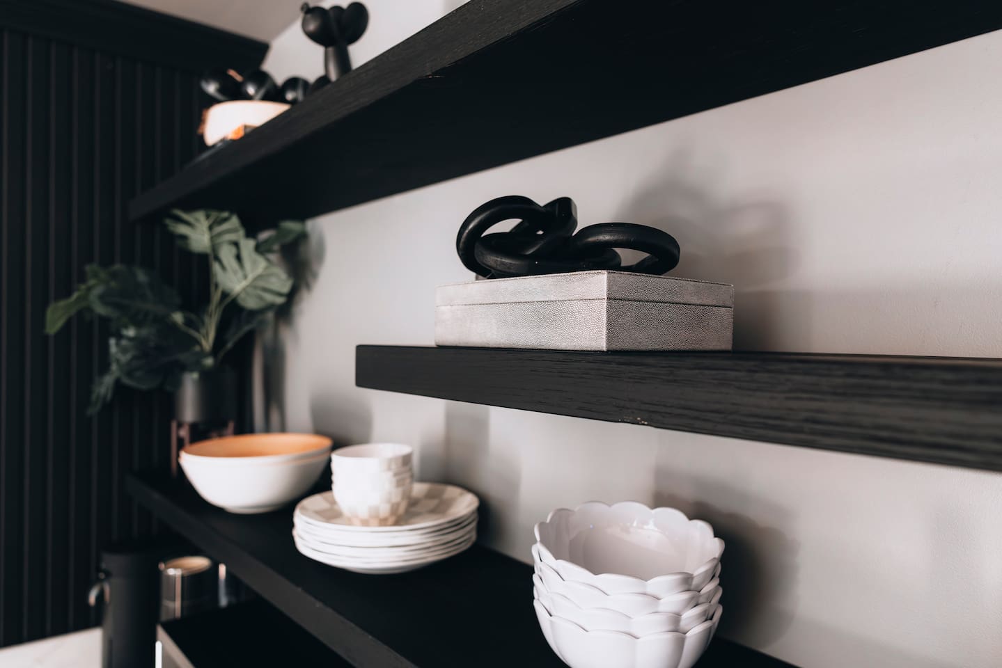 Black floating shelves holding stacked bowls, plates and a lidded box