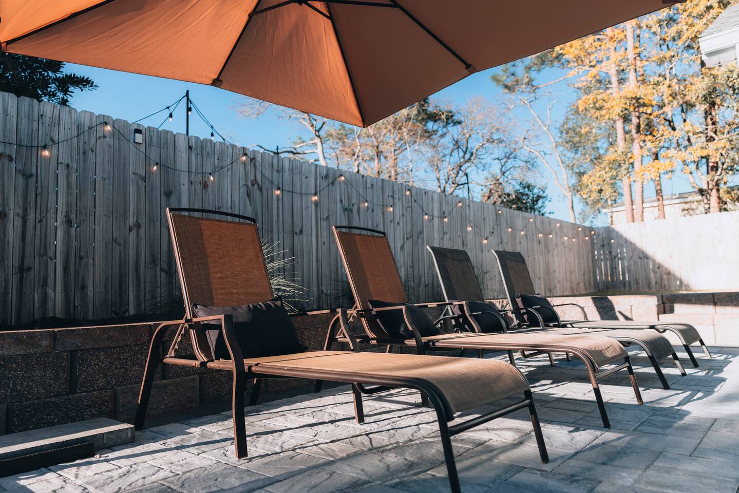 Loungers shaded by a wide umbrella on the paver patio