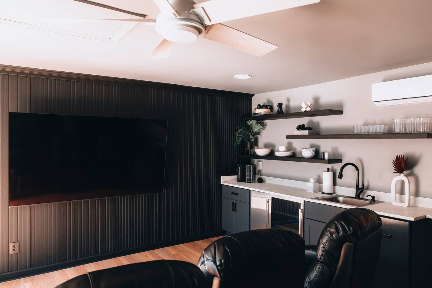 Media room with wall-mounted TV, wet bar sink and beverage fridge