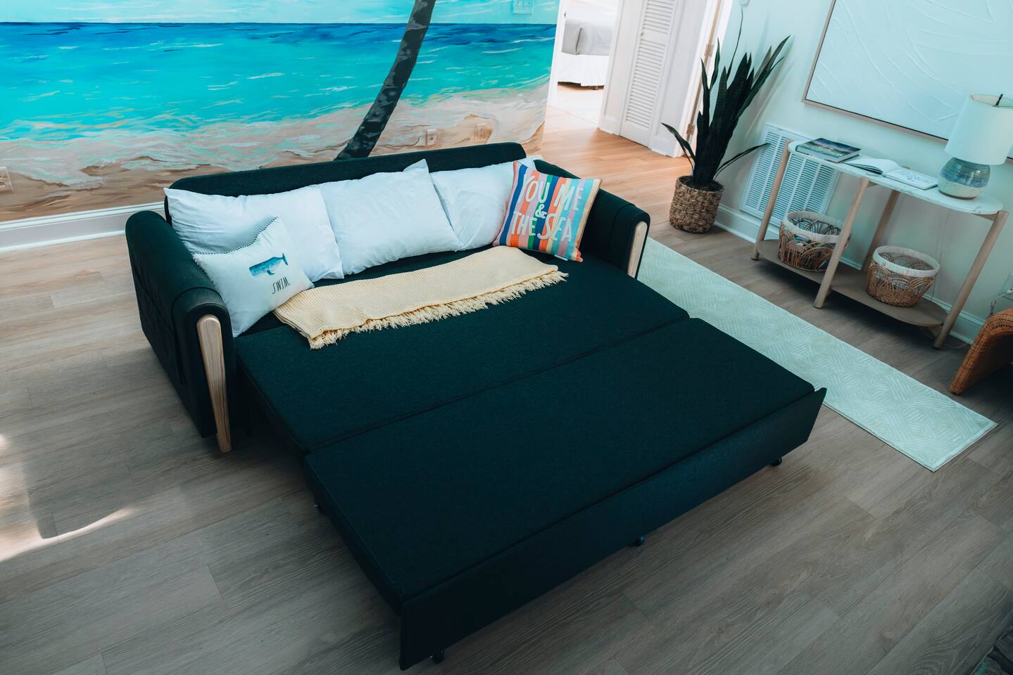 Sofa bed pulled out in front of the painted beach mural