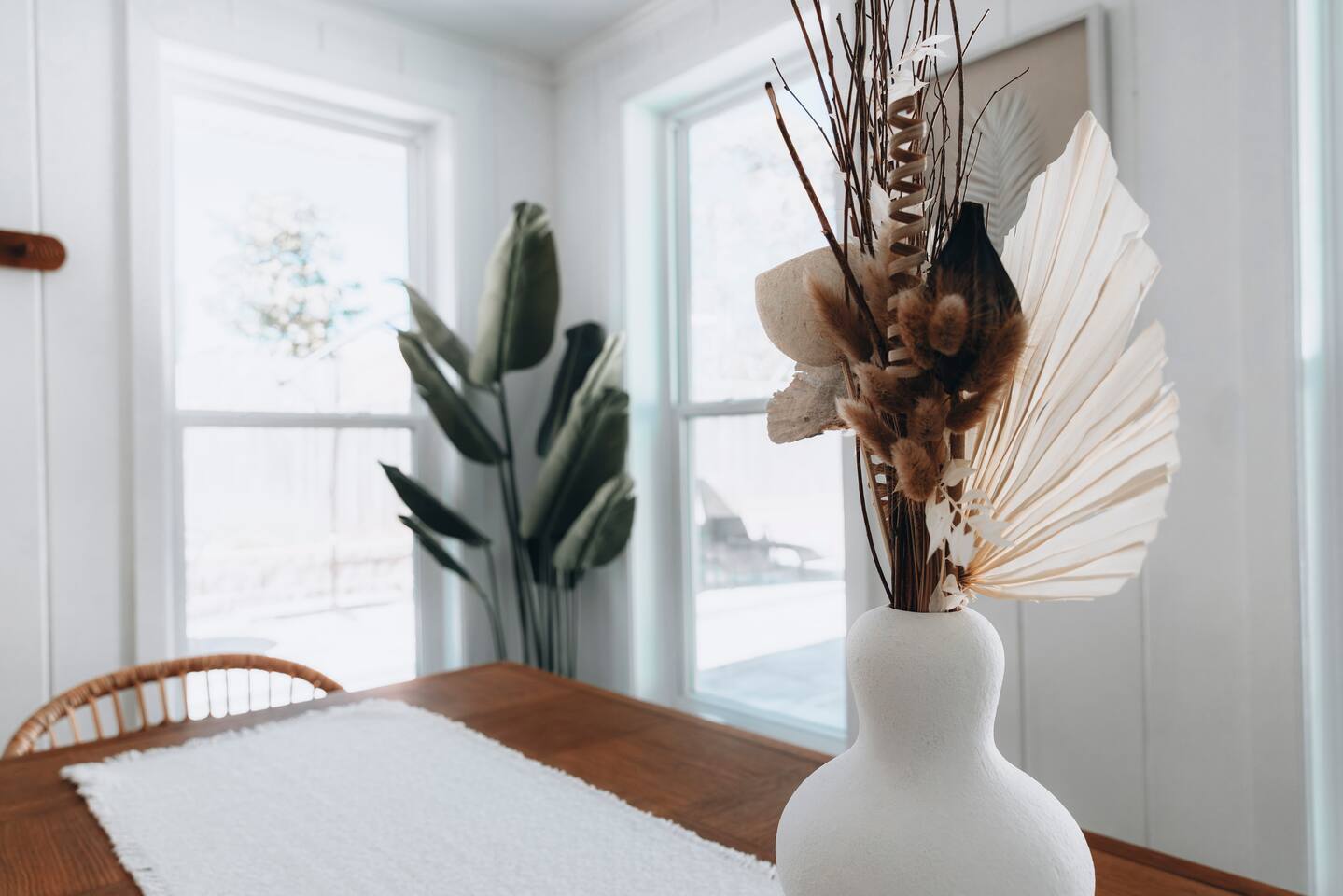 Dried palm arrangement on the dining table beside bright windows