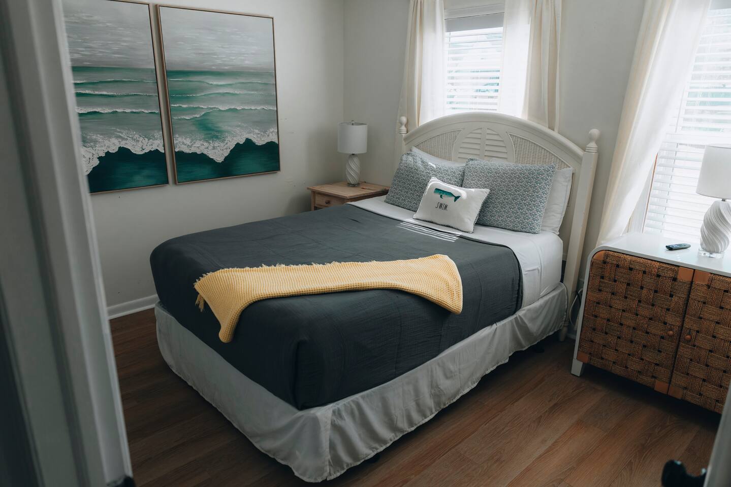 Corner bedroom with white headboard and layered coastal bedding