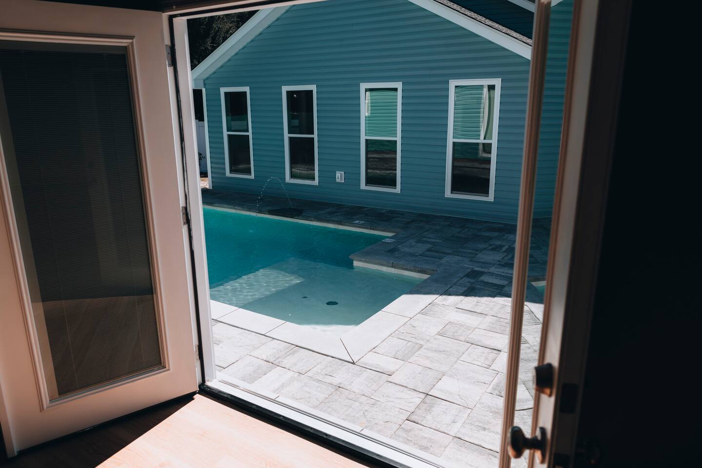 French doors opening straight onto the pool and paver deck