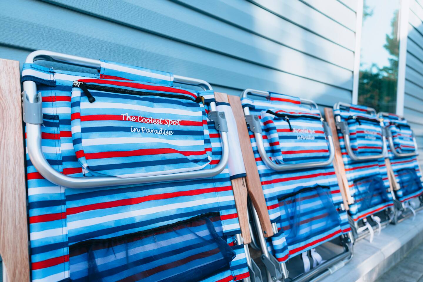 Striped folding beach chairs stacked against the blue siding