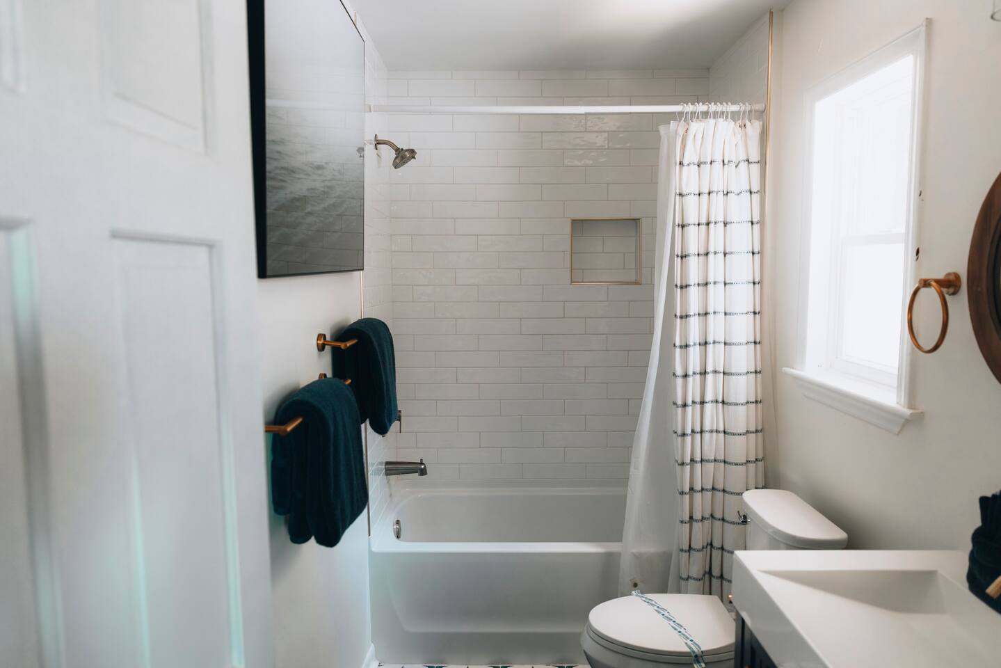 Bathroom with a tiled tub and shower beside a bright window