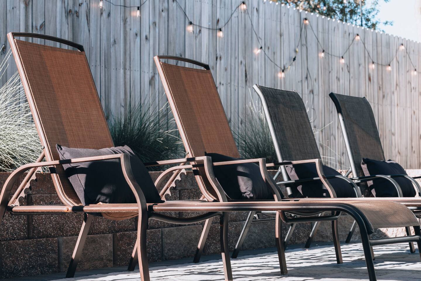 Four sling loungers with cushions along the fenced patio wall