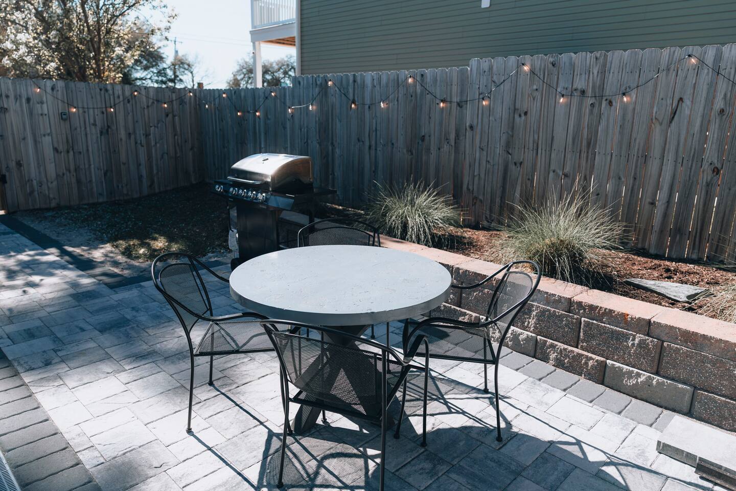 Paver patio with round table, four chairs and a gas grill