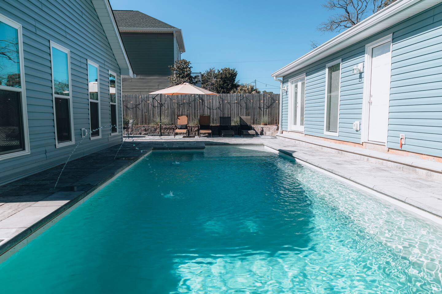 Water jets arcing into the pool, with loungers on the far patio