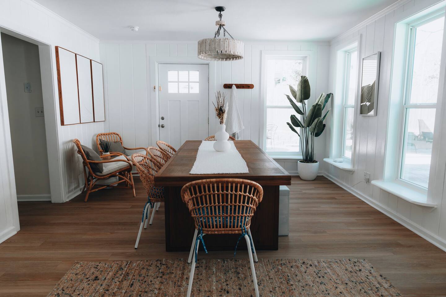 Dining room with a long wood table, rattan chairs and beaded pendant