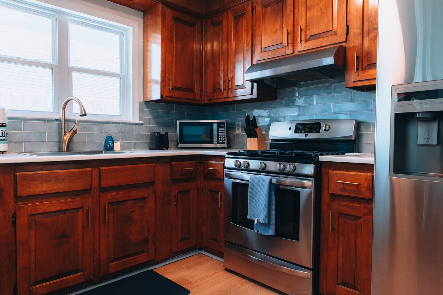 Kitchen with wood cabinets, gas range and green tile backsplash