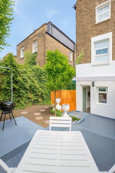 Leafy brick patio with grill, outdoor dining, and garden charm.