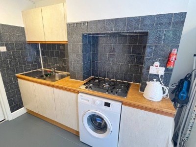Simple kitchen in Shepherd’s Bush with gas cooktop, washer and sleek black tile backsplash. A practical setup just minutes from Hammersmith in West London’s vibrant heart.