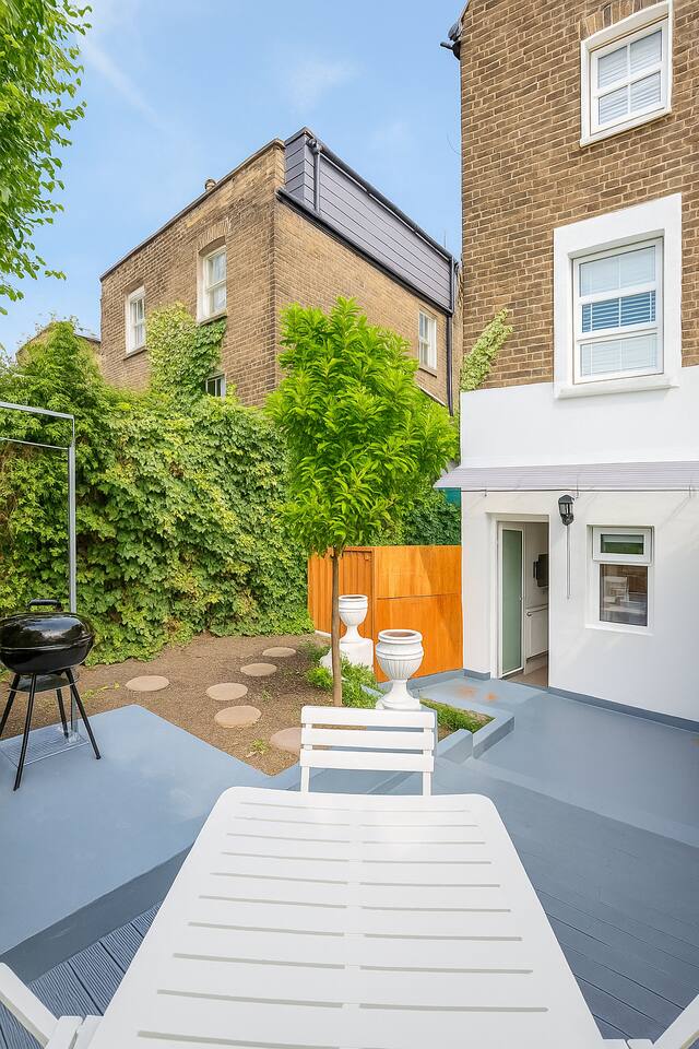 Leafy brick patio with grill, outdoor dining, and garden charm.