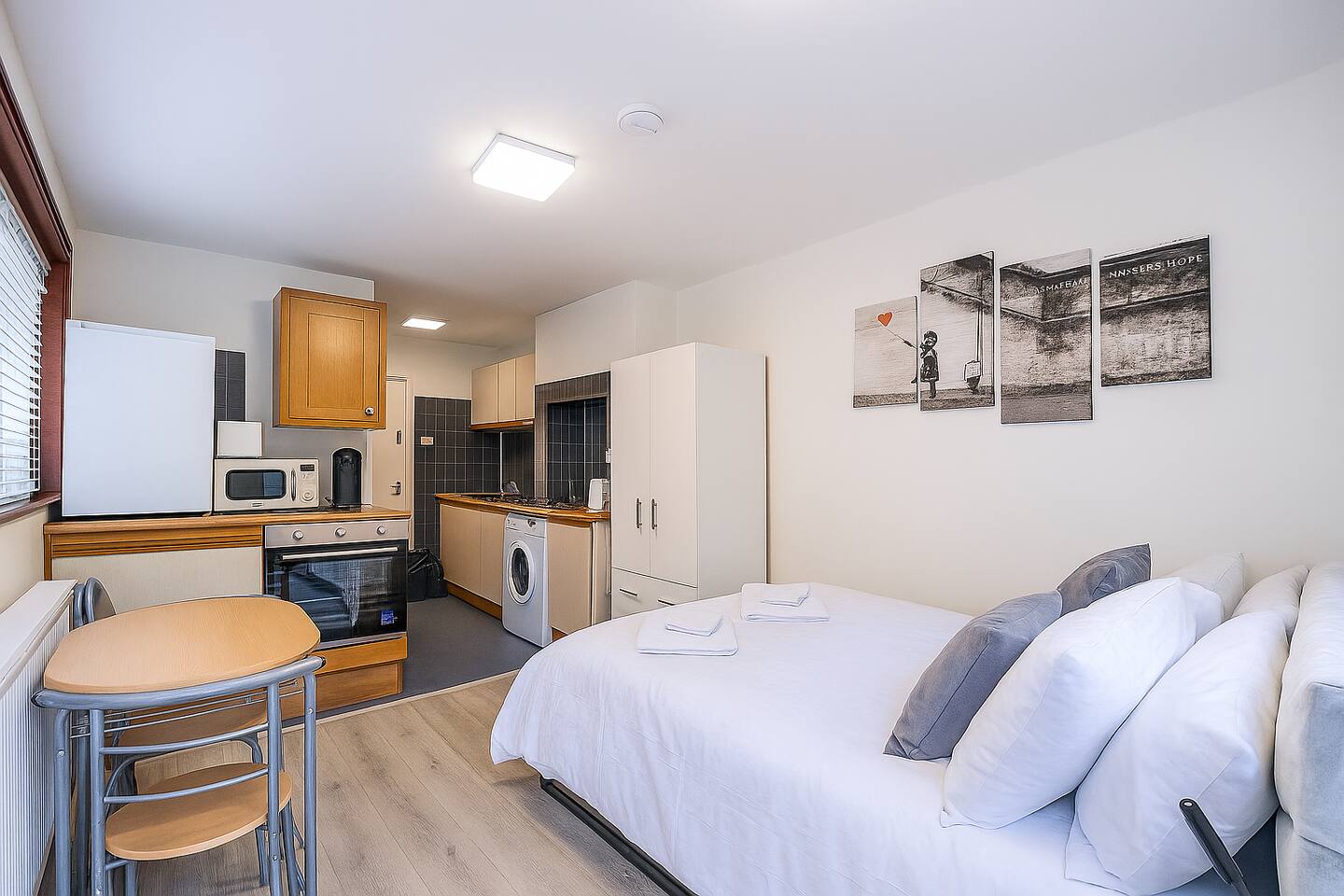 Bright studio in Shepherd’s Bush with cozy bed, full kitchen, dining nook and wall-mounted TV. Just minutes from Westfield London, it’s a clean, open-plan space with modern amenities for short stays.