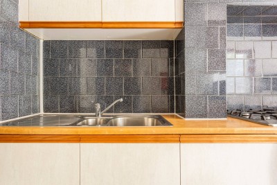Simple kitchen with a gas cooktop, washer, and black tile backsplash.