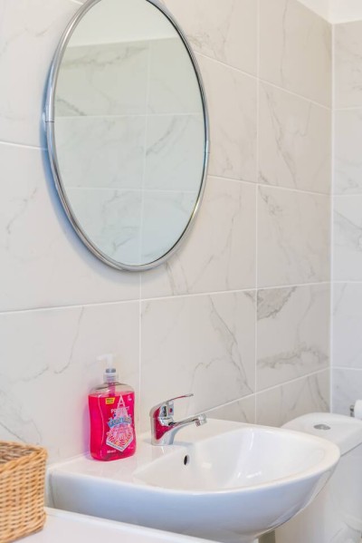 Modern bathroom with sleek sink, round mirror, and marble-style tiles.
