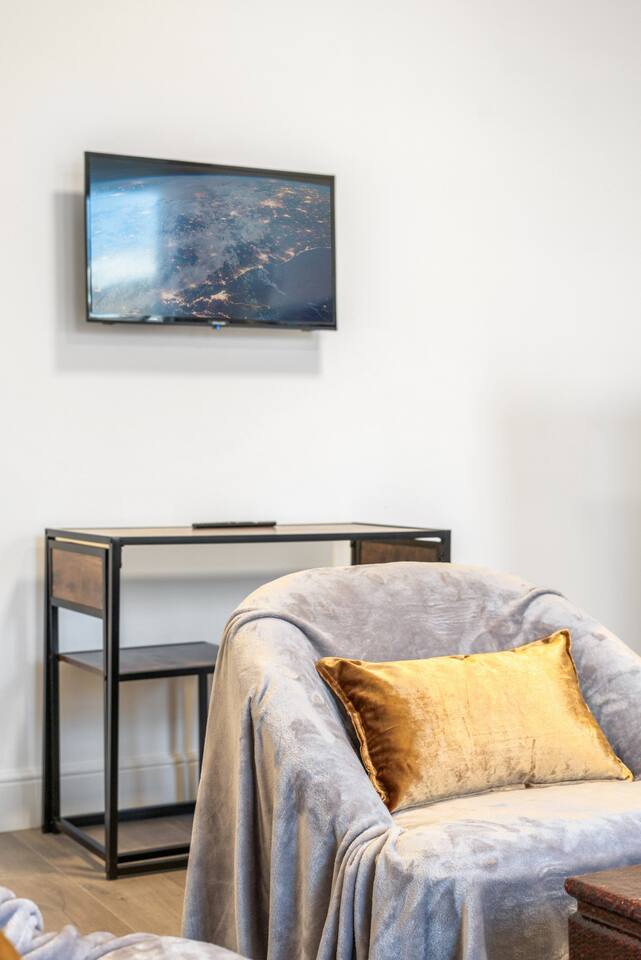 Cozy lounge with smart TV, plush seating, and modern desk setup.