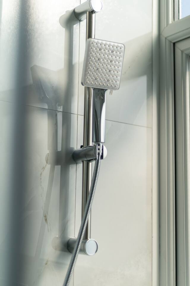 Modern shower with adjustable head and natural light by the window.