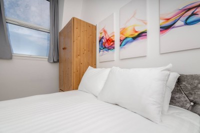 This home on Uxbridge Road, Greater London, moments fromWestfield London, features a cozy bedroom with a comfy bed, soft lighting, and relaxing vibes, ideal for rest after a long day.
