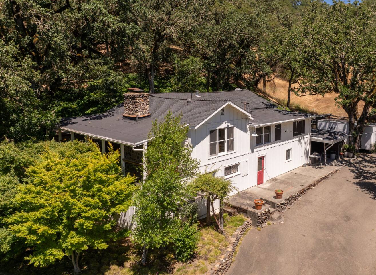 Beautifully landscaped exterior with plenty of open lawn, shaded by lush, towering trees.