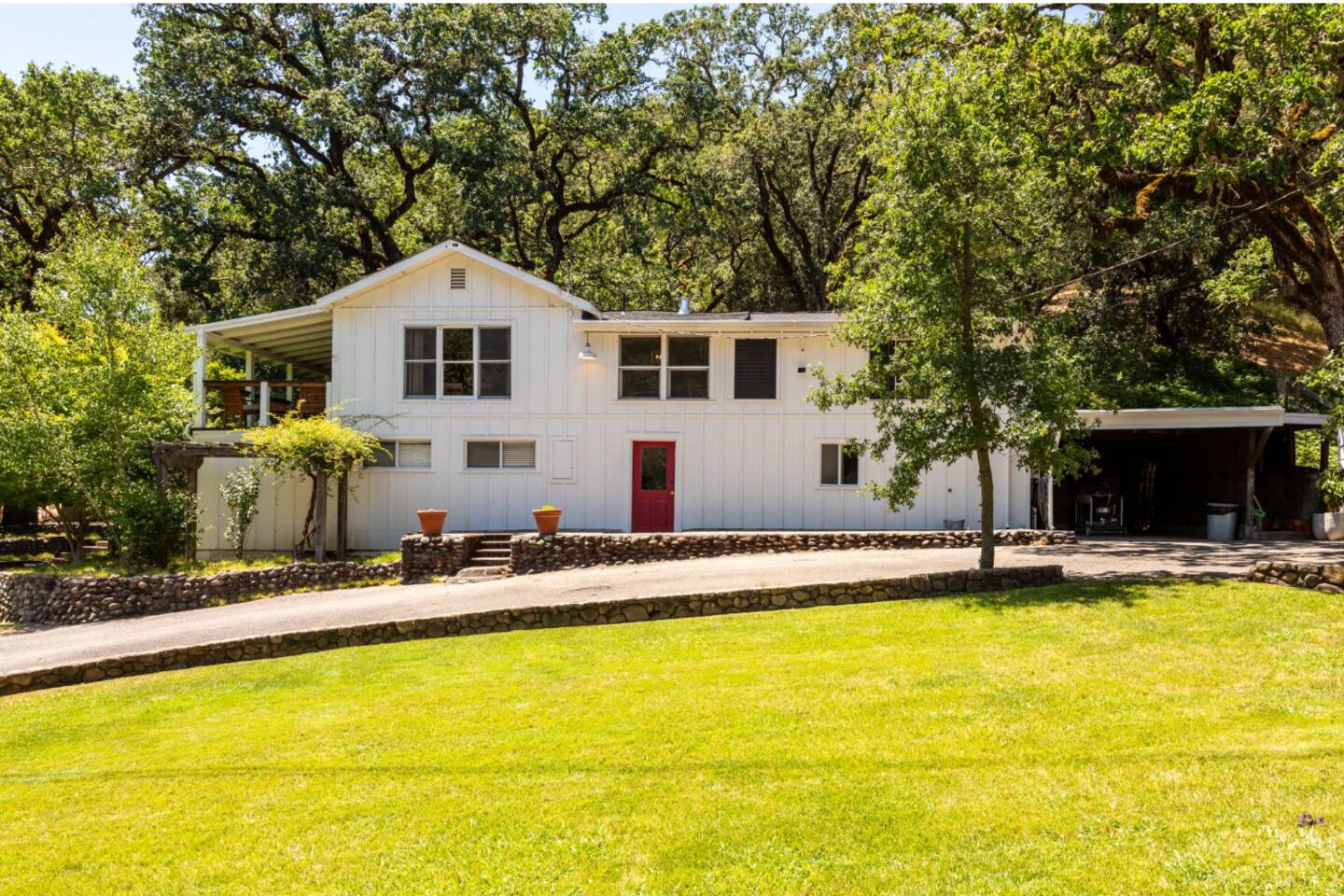 Beautifully landscaped exterior with plenty of open lawn, shaded by lush, towering trees.