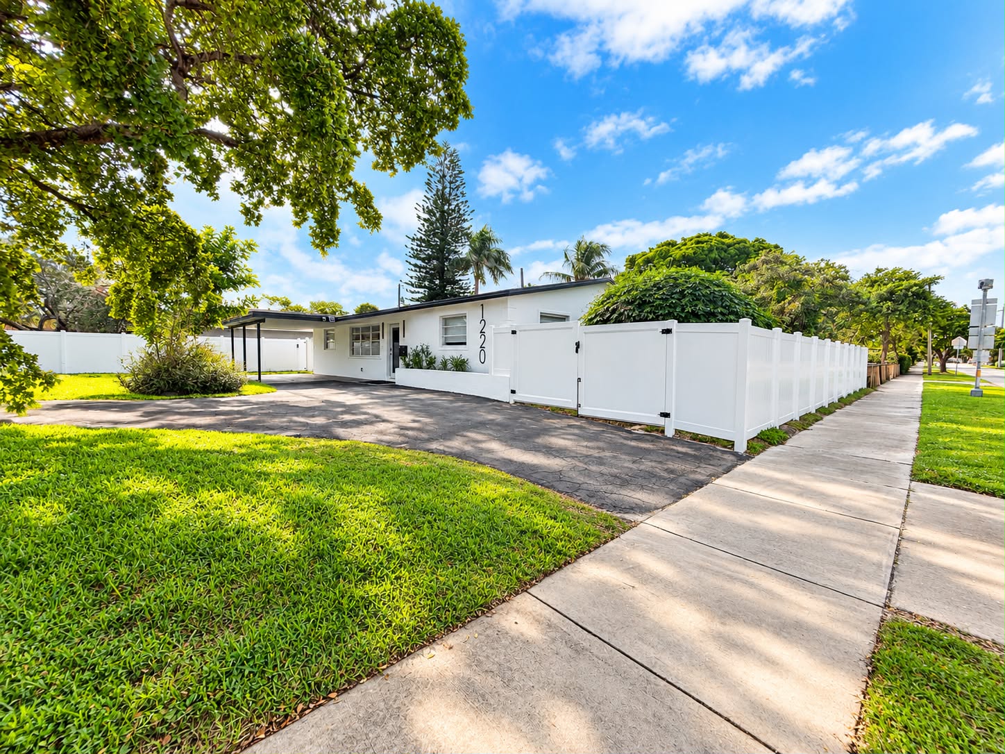 Bright corner-lot home with lush lawn, wide driveway, and privacy fence